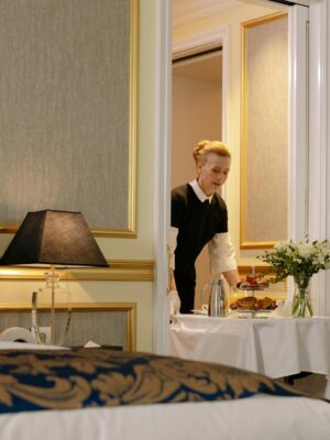 A hotel employee delivers elegant room service with a tray of breakfast in a luxurious hotel setting.