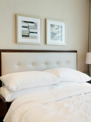 Spacious hotel bedroom featuring modern decor with clean bedding and stylish lamps.
